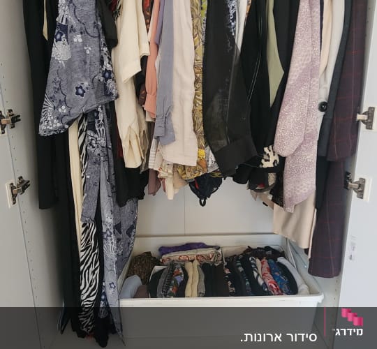 ארון בגדים מאורגן עם בגדים תלויים ומגירות נעליים